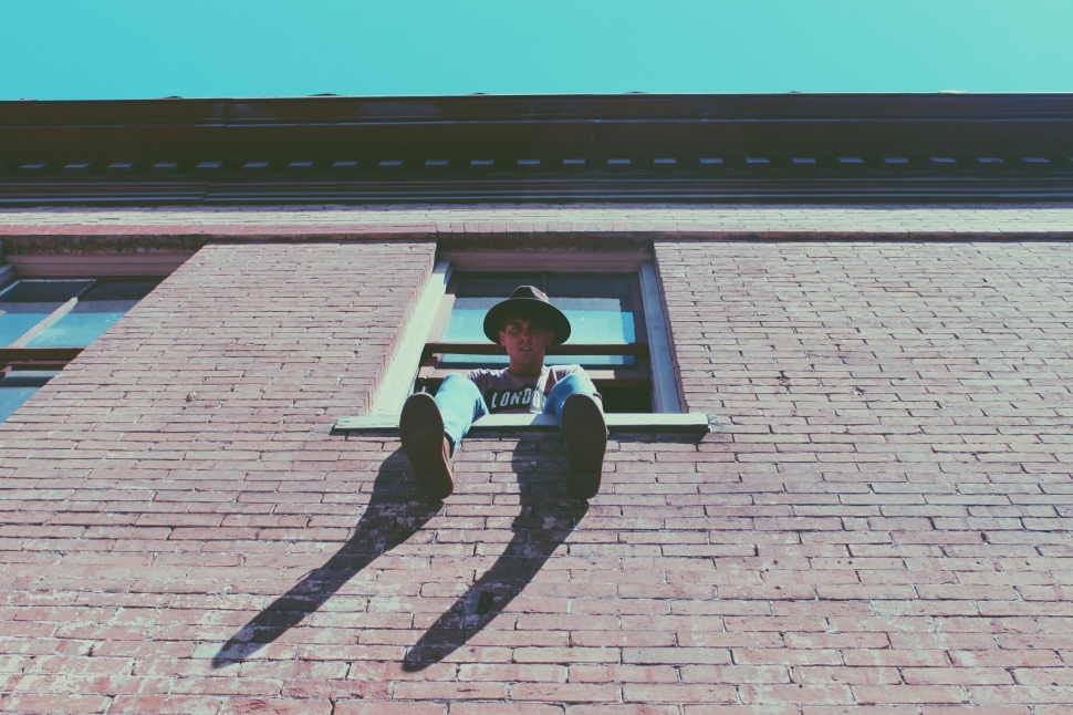 low angle photography of man sitting on window during daytime preview